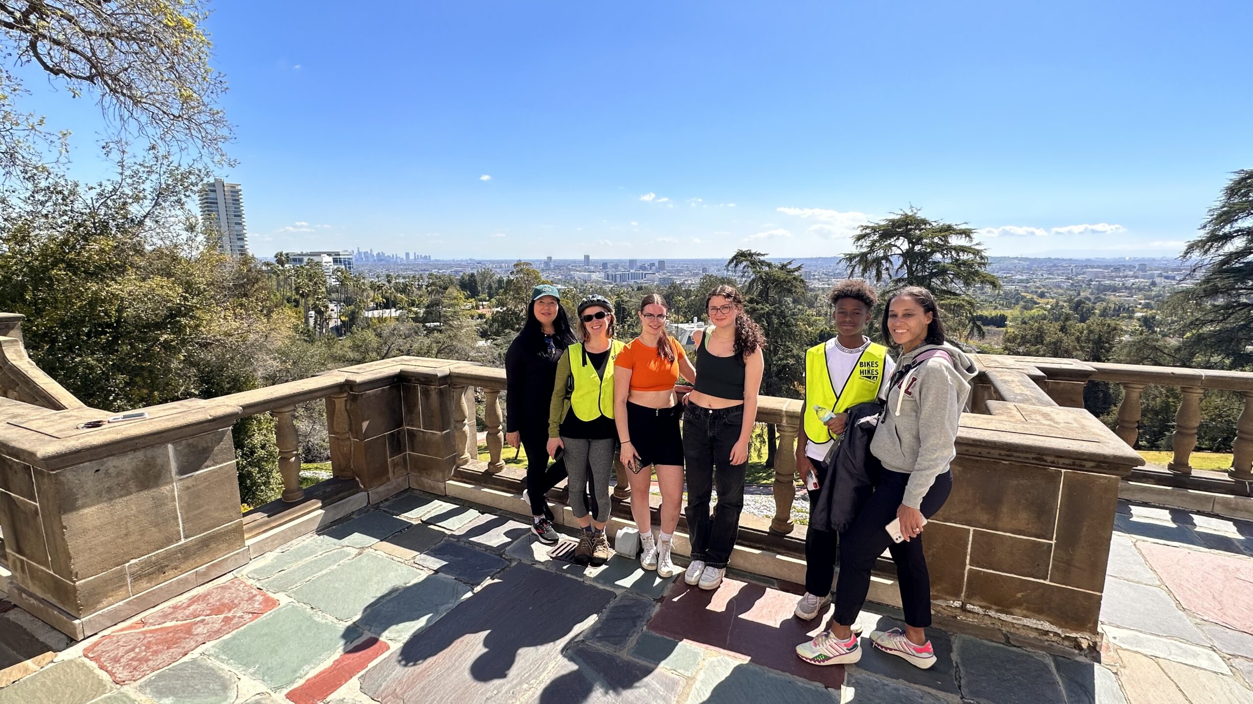 Guests take a photo on the balcony at greystone mansion on the beverly hills tour overlooking los angeles