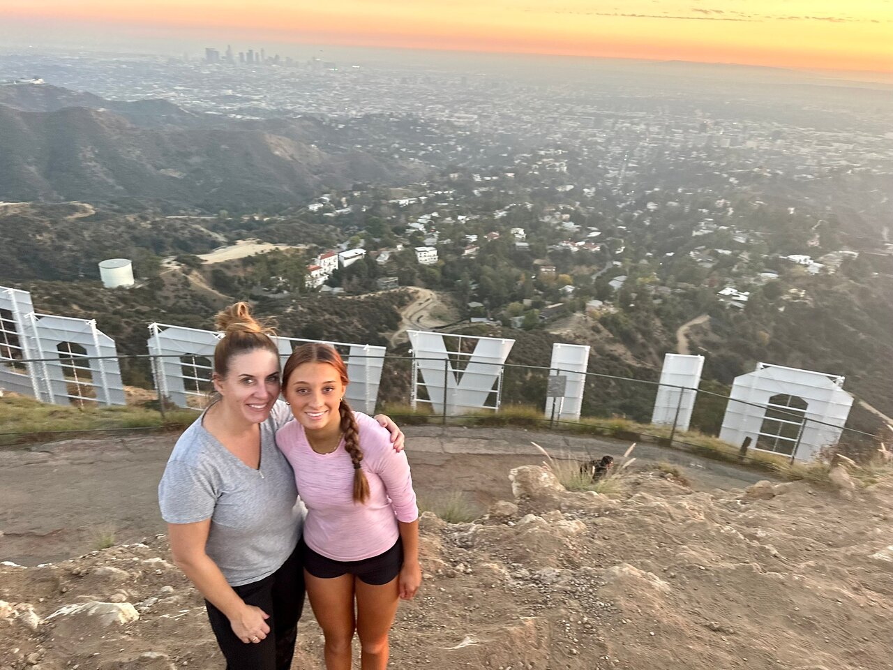 Two girls pose behind the Hollywood Sign on the Hollywood Sign Hike at Sunset