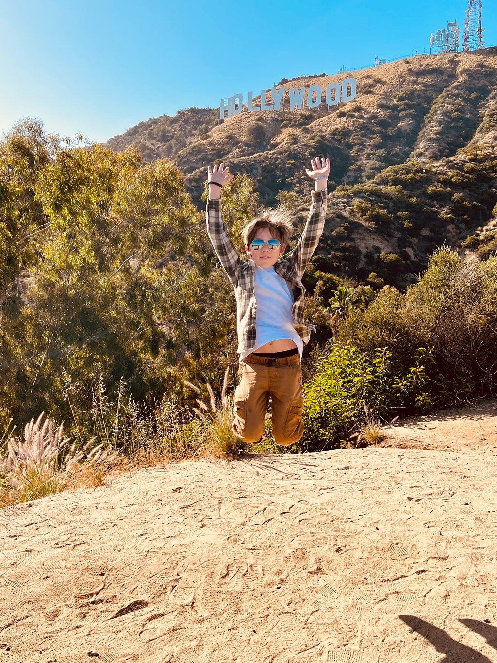 A boy jumps on the Hollywood Sign Tour in front of the Hollywood Sign