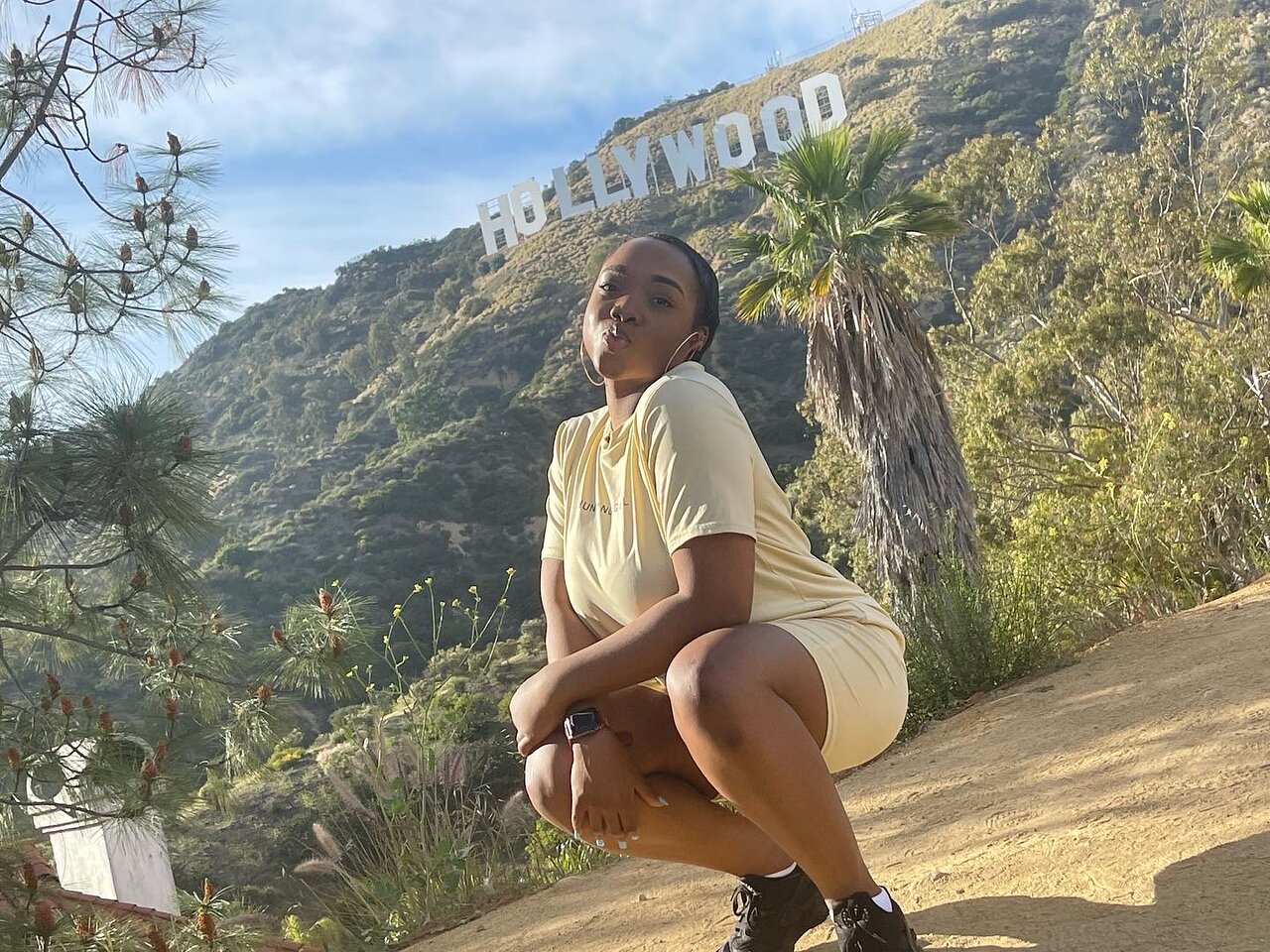 A young girl poses in front of the Hollywood Sign on the Hollywood sign tour