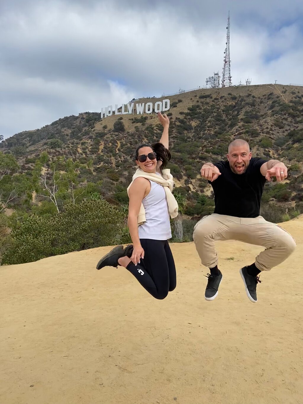 A couple jumps to seem as if they are touching the Hollywood Sign on the Hollywood Sign Tour