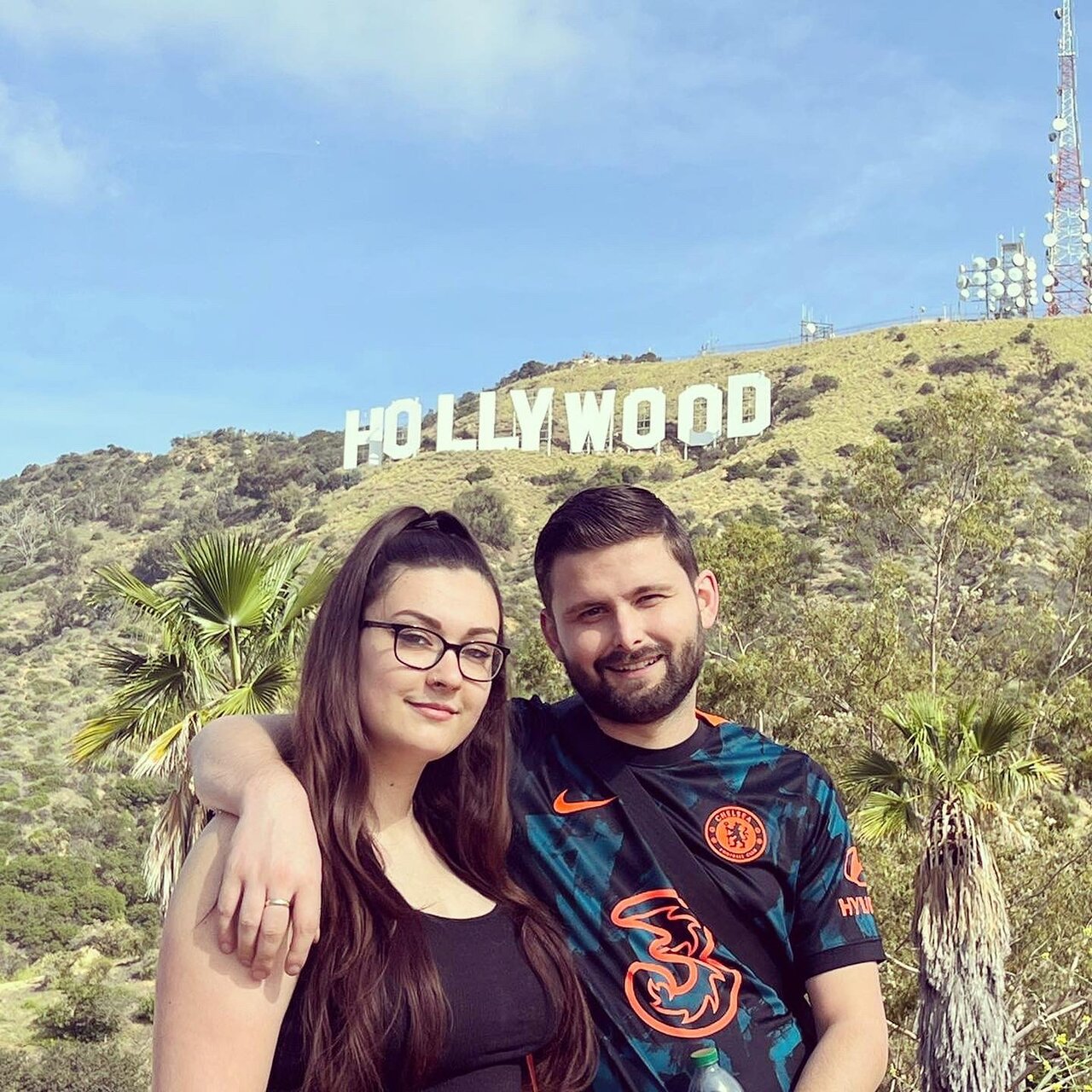A couple poses underneath the Hollywood Sign on the Hollywood Sign Tour