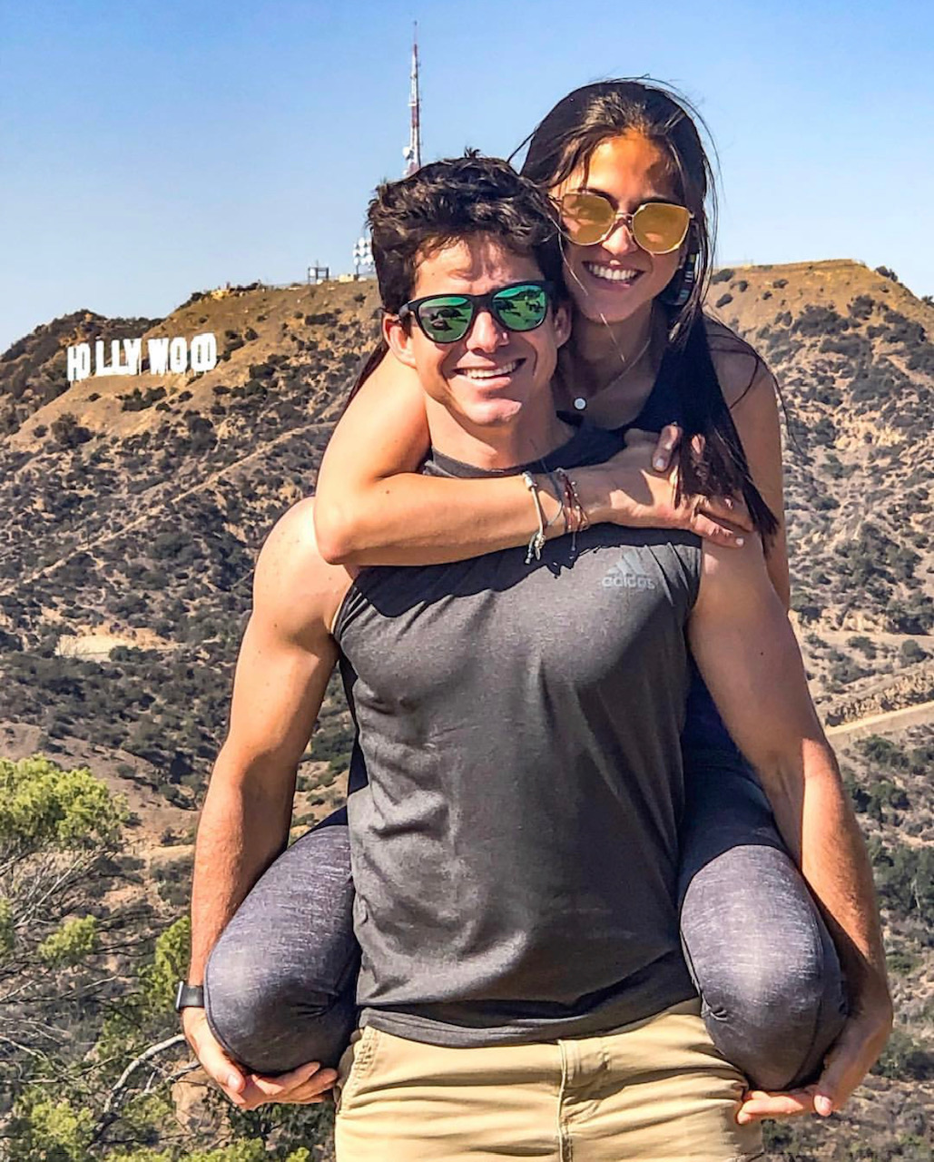 A couple smiles with the hollywood sign in the background on our Griffith Observatory tour