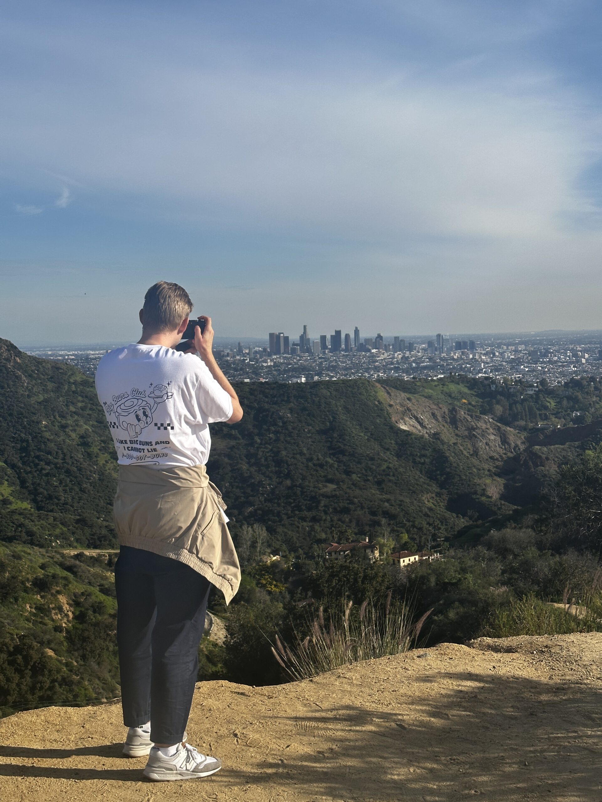 A guest on the Hollywood Sign hike takes a photo of the Downtown LA skyline