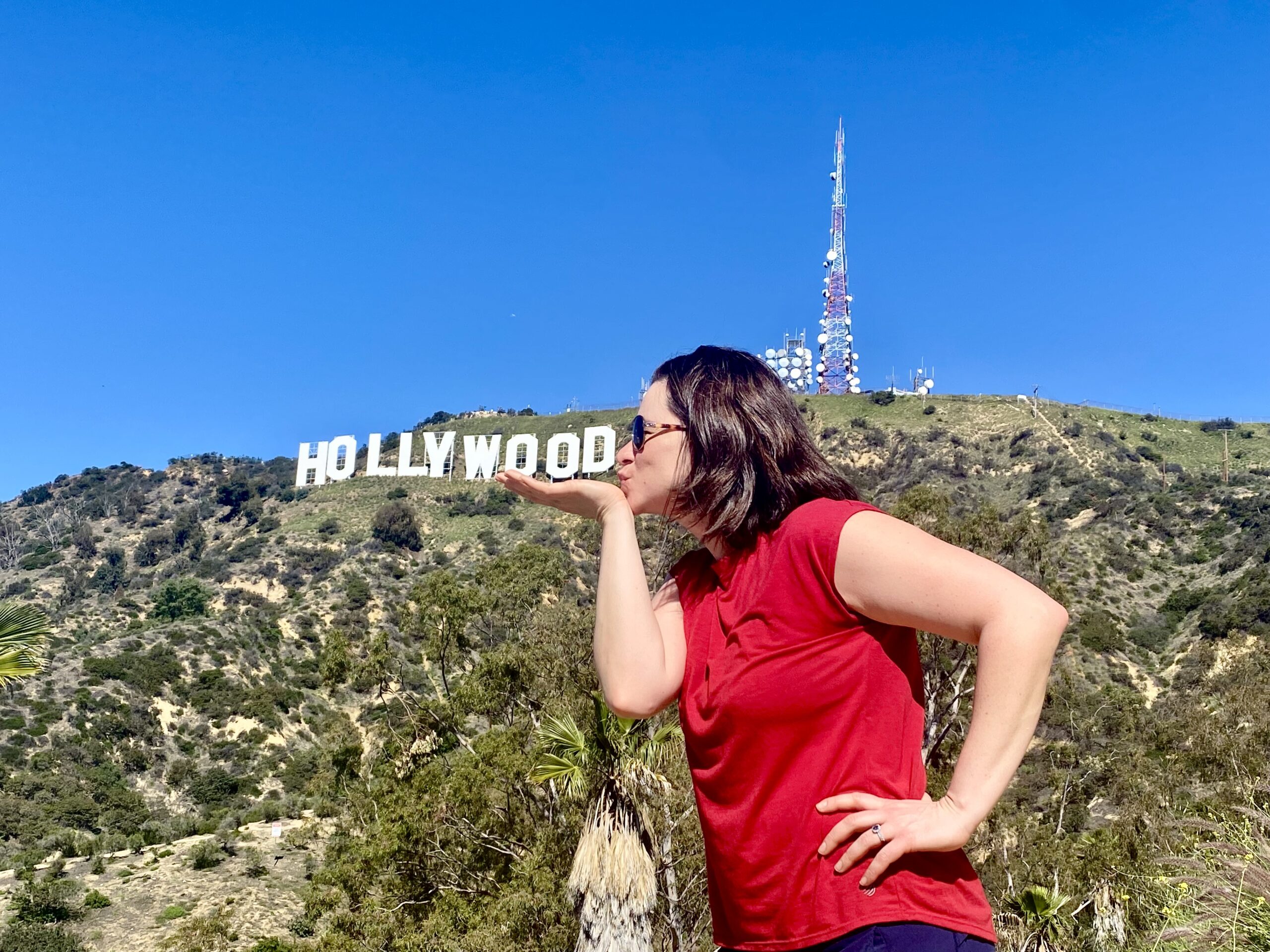 A guest on the Hollywood Sign hike poses with the Hollywood Sign, pretending to kiss it.