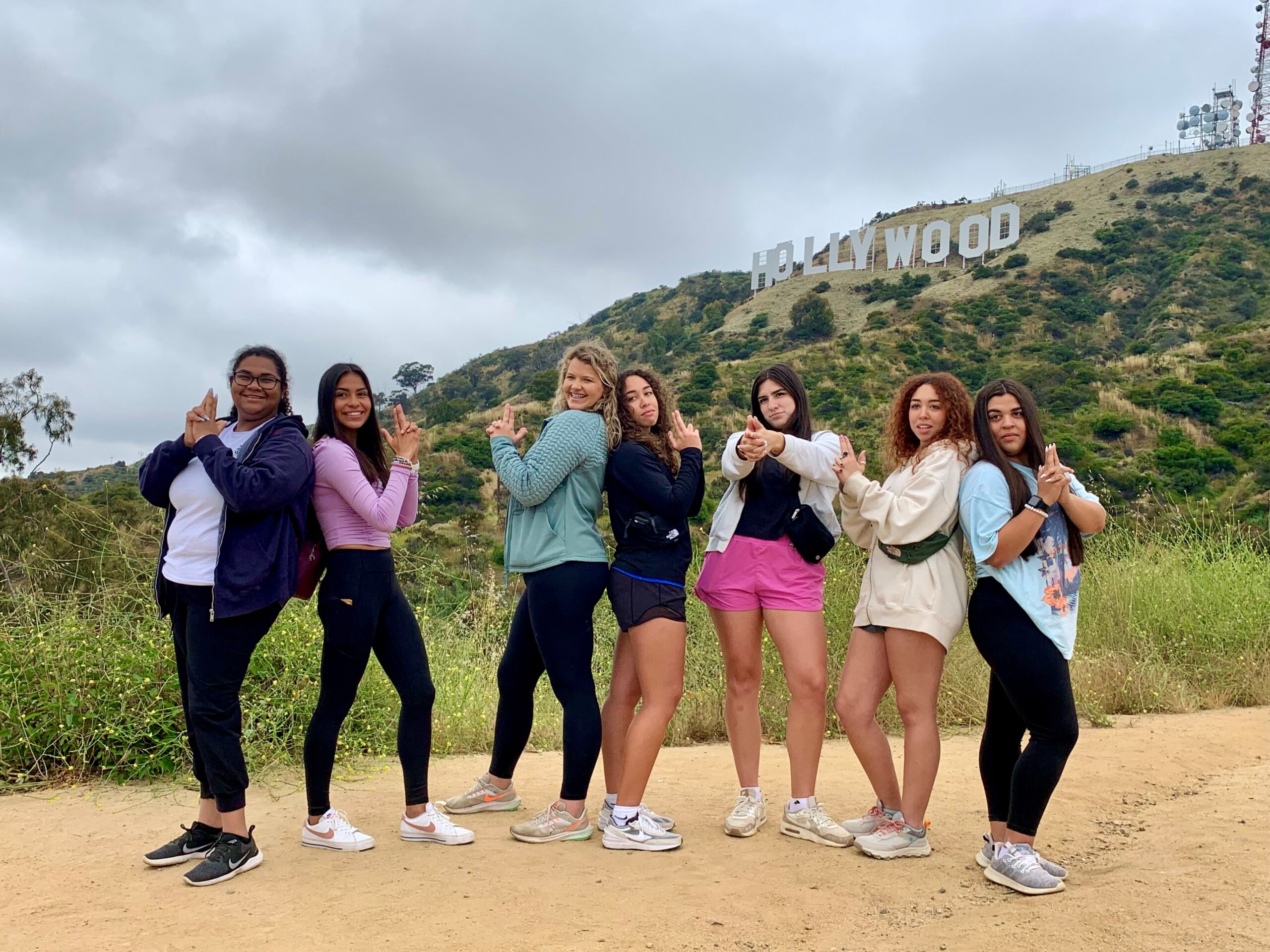 A group of girls pose like charlie's angels in front of the Hollywood Sign on our Hollywood Sign Tour